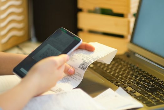 Unrecognizable woman scans store receipts using a smartphone.
